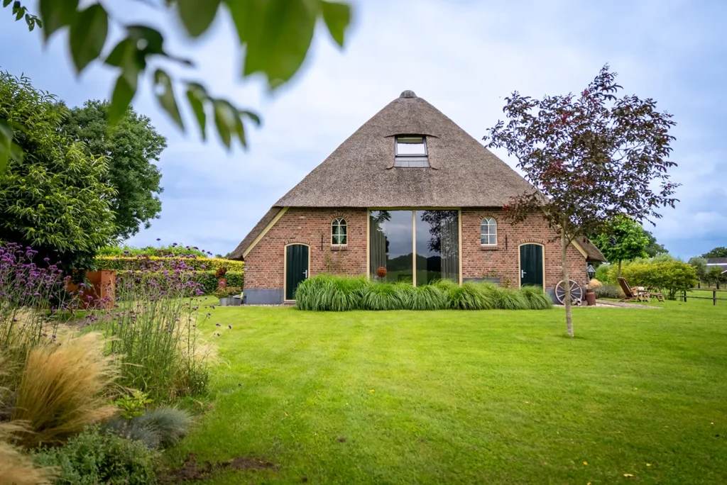 Achterzijde van de verbouwde boerderij met glas in oude staldeuren