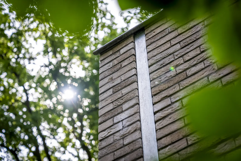 Detail van geïntegreerde zinken regenpijp. Vakmanschap en materiaalcombinatie van Mensink Bouwbedrijf.