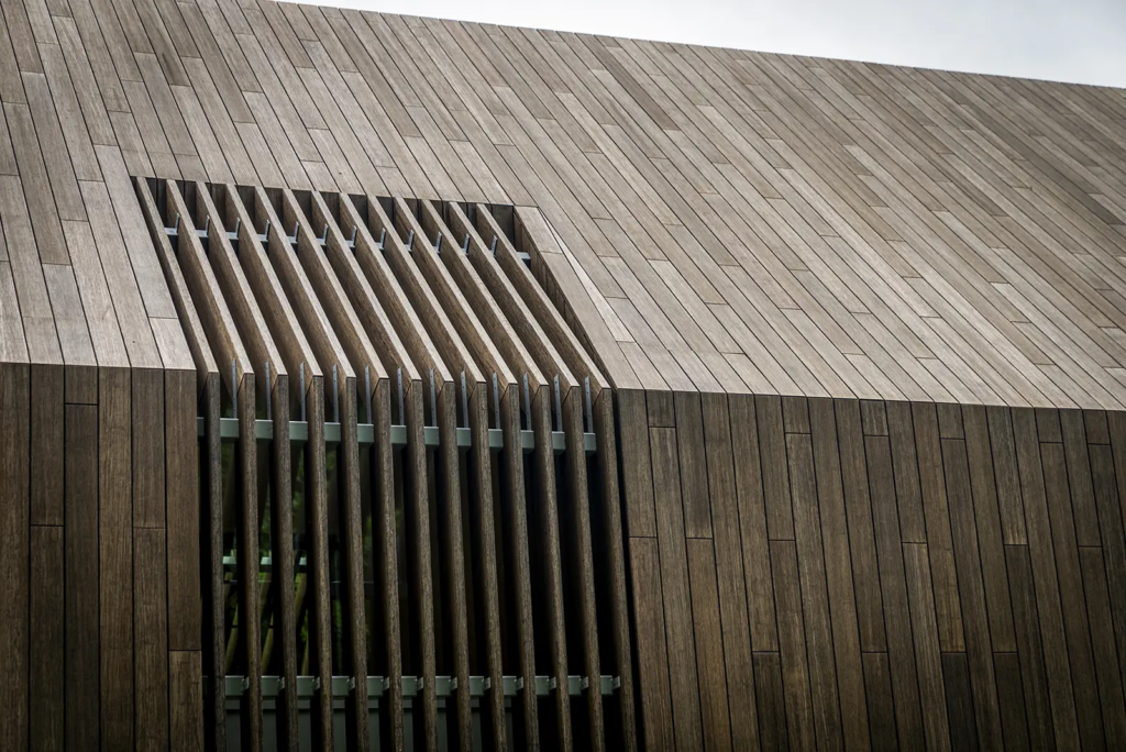 Detail van houten gevel met verticale lamellen, duurzaam materiaalgebruik en strak vakwerk van Mensink.