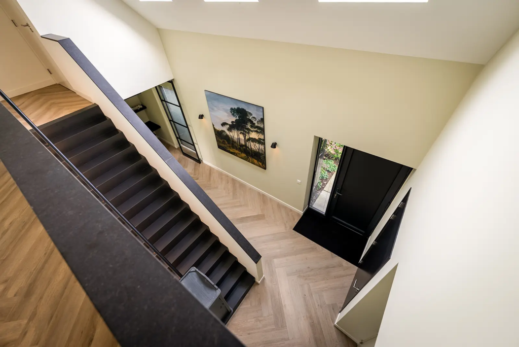 Ruime hal met moderne trap en veel lichtinval in woning Gorssel, ontworpen door Mensink Bouwbedrijf.