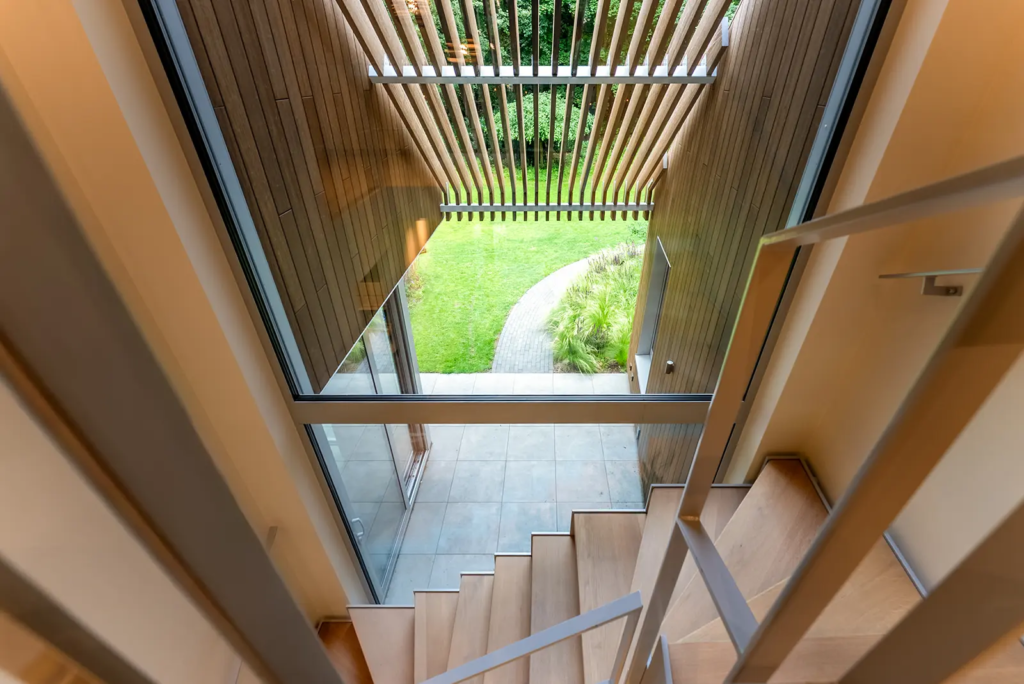 Modern trappenhuis met houten lamellen en uitzicht op de groene tuin, gebouwd door Mensink Bouwbedrijf in Berkum.