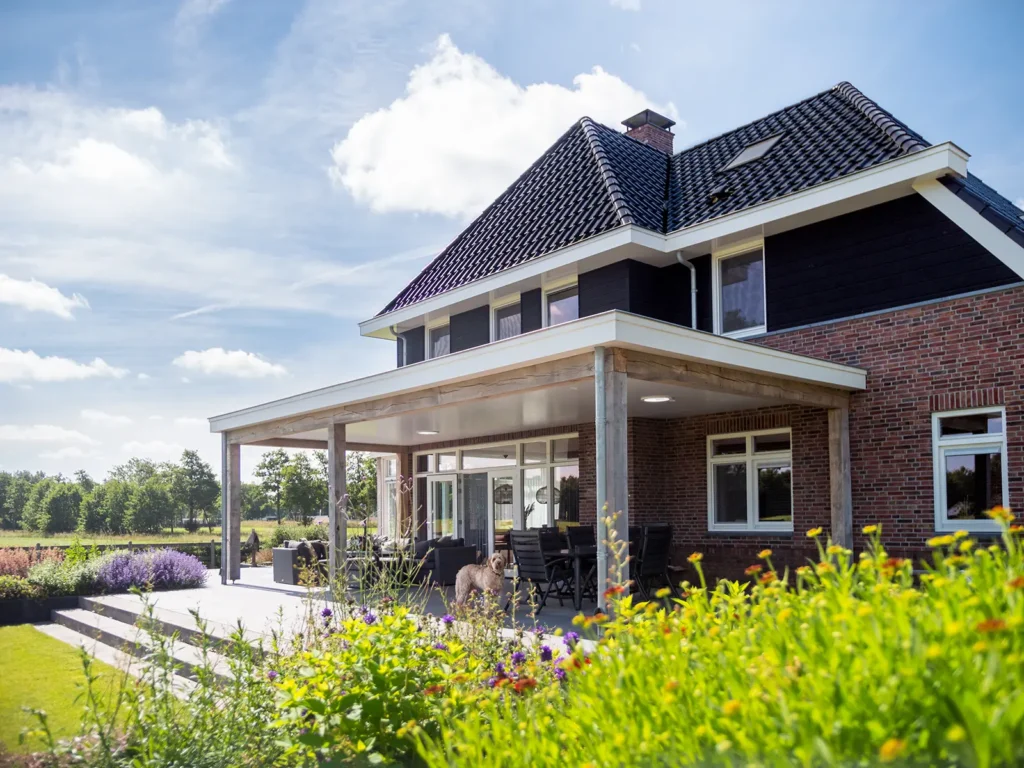Achterzijde van de woning in Heerde met royale veranda, zithoek en uitzicht over het groene landschap.