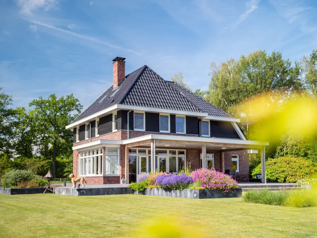 Achterzijde van de woning in Heerde met royale veranda, zithoek en uitzicht over het groene landschap.