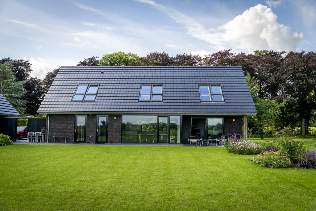 Achterzijde van moderne schuurwoning met terras en tuin, ontworpen door Mensink Bouwbedrijf in Olst.