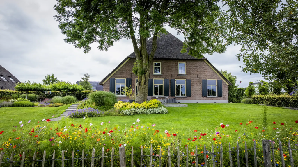 Voorzijde van gerestaureerde woonboerderij met grote tuin in Okkenbroek, door Mensink Bouwbedrijf.