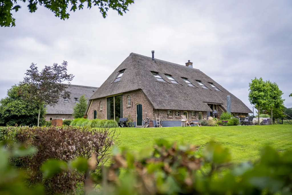 Gerestaureerde woonboerderij met rieten dak en karakteristieke details in Okkenbroek, gebouwd door Mensink.
