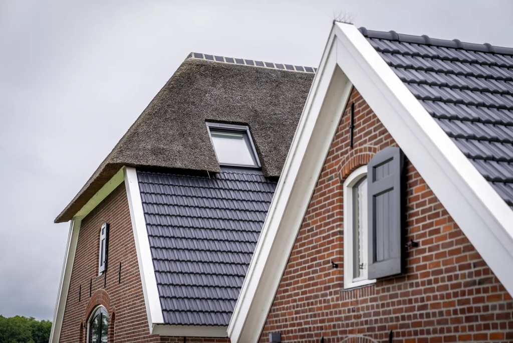 Detail van daklijn en gevel met houten luiken bij woonboerderij in Okkenbroek.