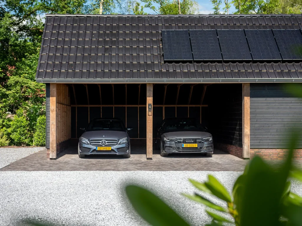 Dubbele carport bij de woning in Heerde met houten constructie, zwarte dakpannen en zonnepanelen op het dak.