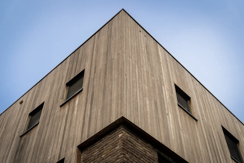 Hoekgevel van een moderne kubistische woning in Deventer met veel raampartijen en een combinatie van hout en metselwerk.
