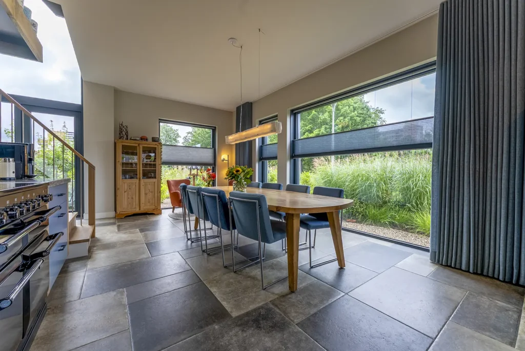 Open keuken met eetruimte in de kubistische woning in Deventer, strak vormgegeven met veel daglicht en verbinding met buiten.