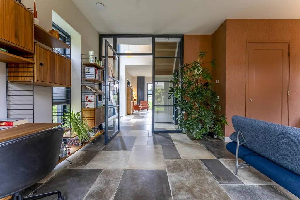 Woonkamer van de kubistische woning in Deventer met veel lichtinval, houten vloer en uitzicht op het groen.