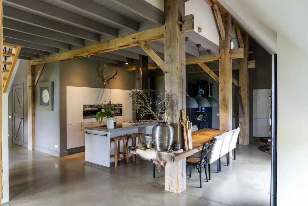 Keuken en eethoek met robuuste houten gebinten in woonboerderij in Okkenbroek met vakmanschap van Mensink.