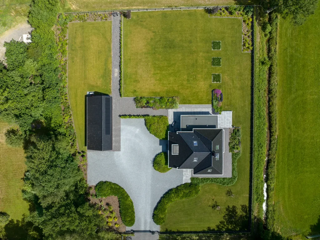Luchtfoto van het perceel en de woning in Heerde met royale tuin, oprijlaan en vrijstaande carport.
