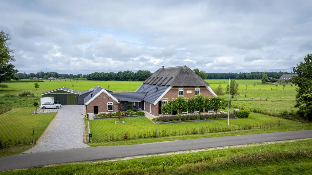Luchtfoto van gerestaureerde woonboerderij en bijgebouw in Okkenbroek, gerealiseerd door Mensink Bouwbedrijf.