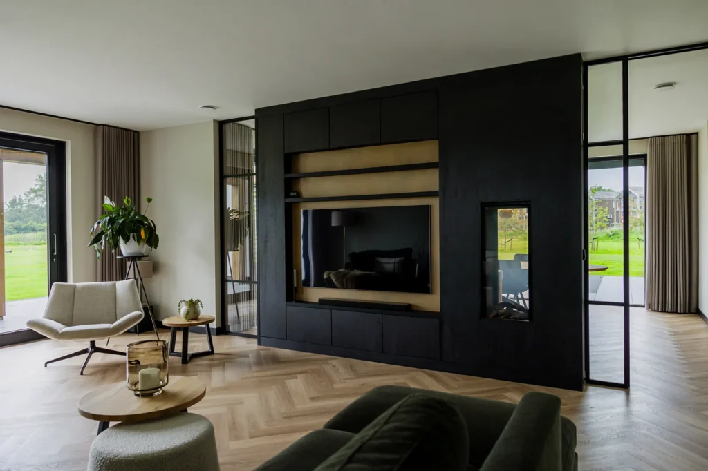Maatwerk wandkast met doorkijkhaard en stalen scheidingswand in een schuurwoning in Lettele, uitgevoerd in donker hout en natuurlijke materialen.