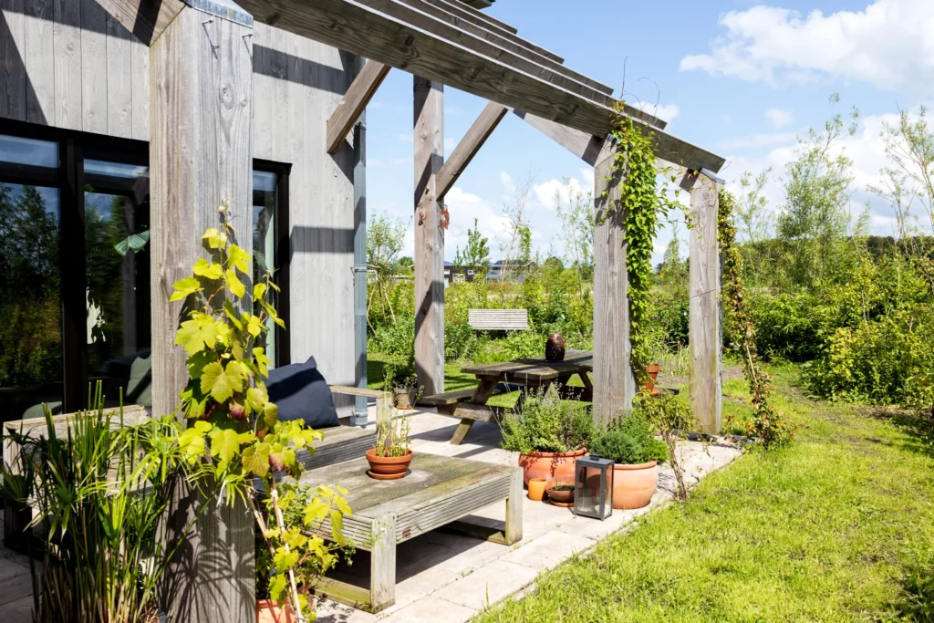 Terras met houten overkapping en planten rondom de biobased woning in de wijk Olstergaard.