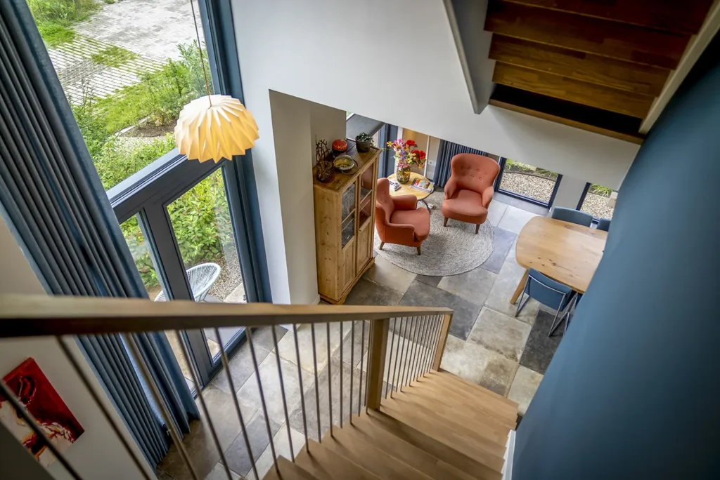 Houten trap in hal met veel lichtinval in de kubistische woning in Deventer, waar architectuur en wooncomfort samenkomen.