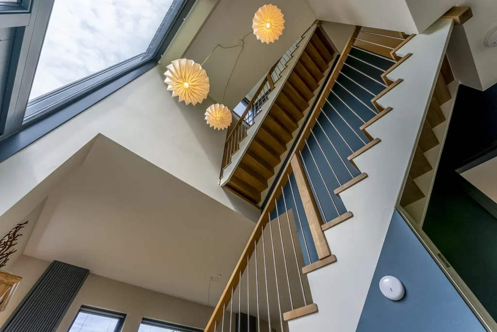Houten trappen in ruime hal met veel lichtinval in de kubistische woning in Deventer, waar architectuur en wooncomfort samenkomen.