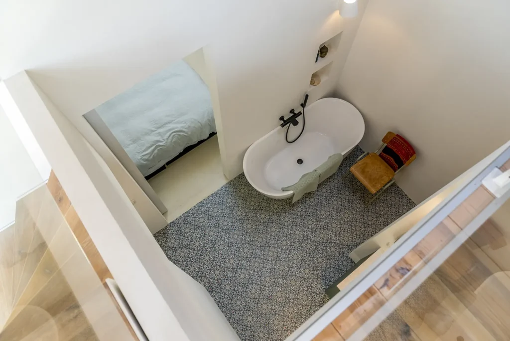 Compacte badkamer met vrijstaand bad en speelse tegelvloer in een tinyhouse in Deventer.