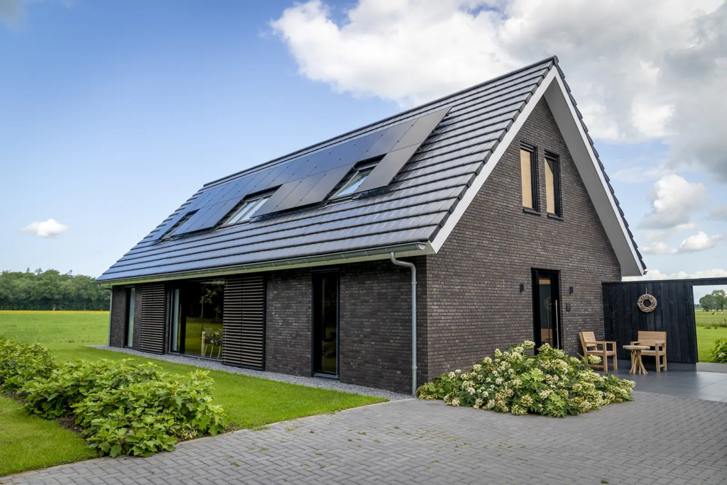 Vooraanzicht van duurzame schuurwoning met zonnepanelen en donkere gevelsteen in Olst.