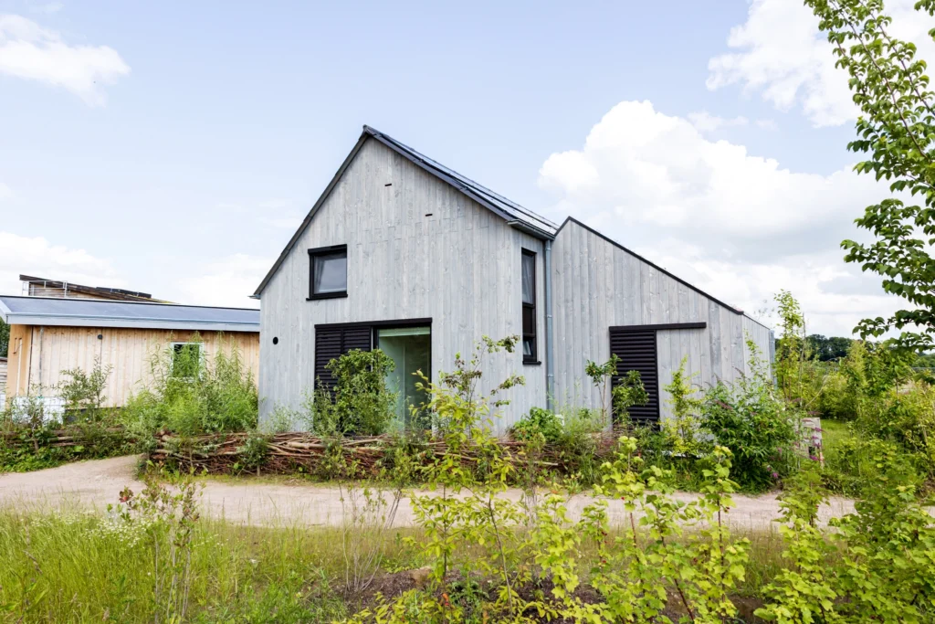 Vooraanzicht van de biobased nieuwbouwwoning in de wijk Olstergaard te Olst met houten gevel en groene omgeving.