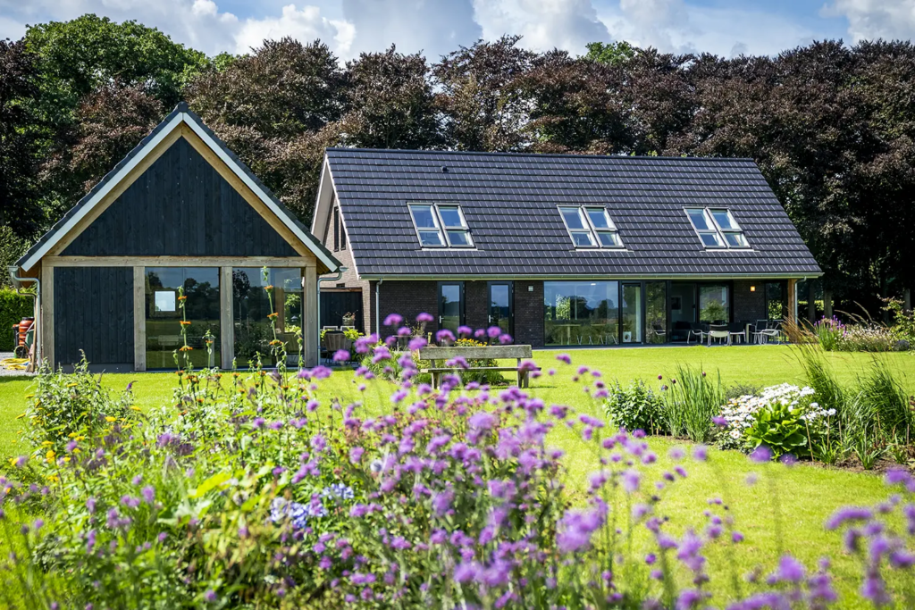 Achterkant van schuurwoning met zwart houten bijgebouw en ruime tuin in Olst, duurzaam gebouwd door Mensink.