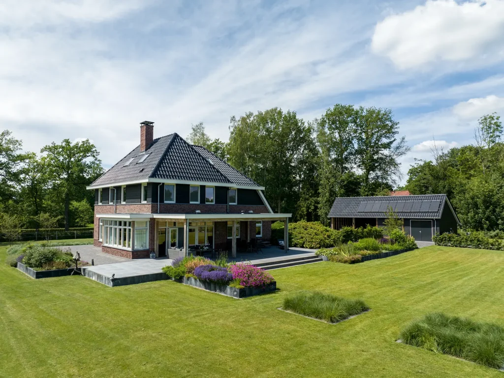 Overzicht van de woning en carport in Heerde met verzorgde tuin, veranda en landelijke uitstraling.
