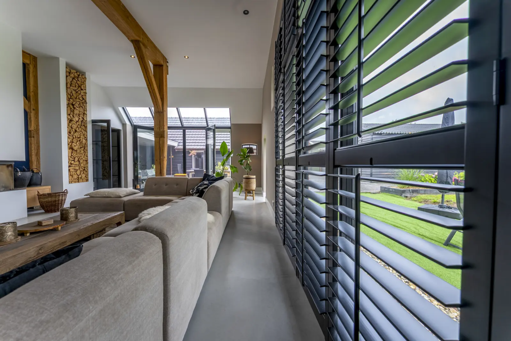 Sfeervolle landelijke woonkamer met houtkachel, veel licht en robuuste houten constructie in woonboerderij Okkenbroek.