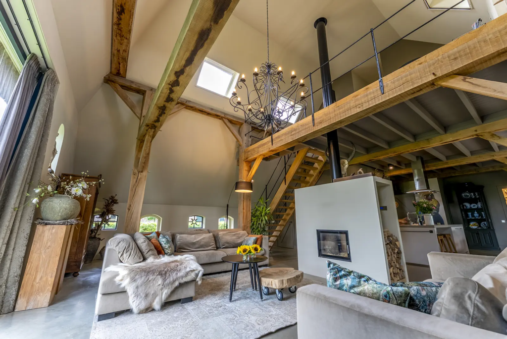 Landelijke woonkamer met vide, houtkachel en zichtbare houten gebinten in woonboerderij Okkenbroek.