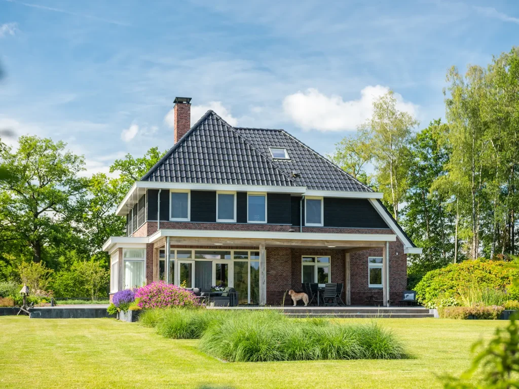 Zijaanzicht van de woning in Heerde met karakteristieke dakvorm, rode baksteen en moderne raampartijen.