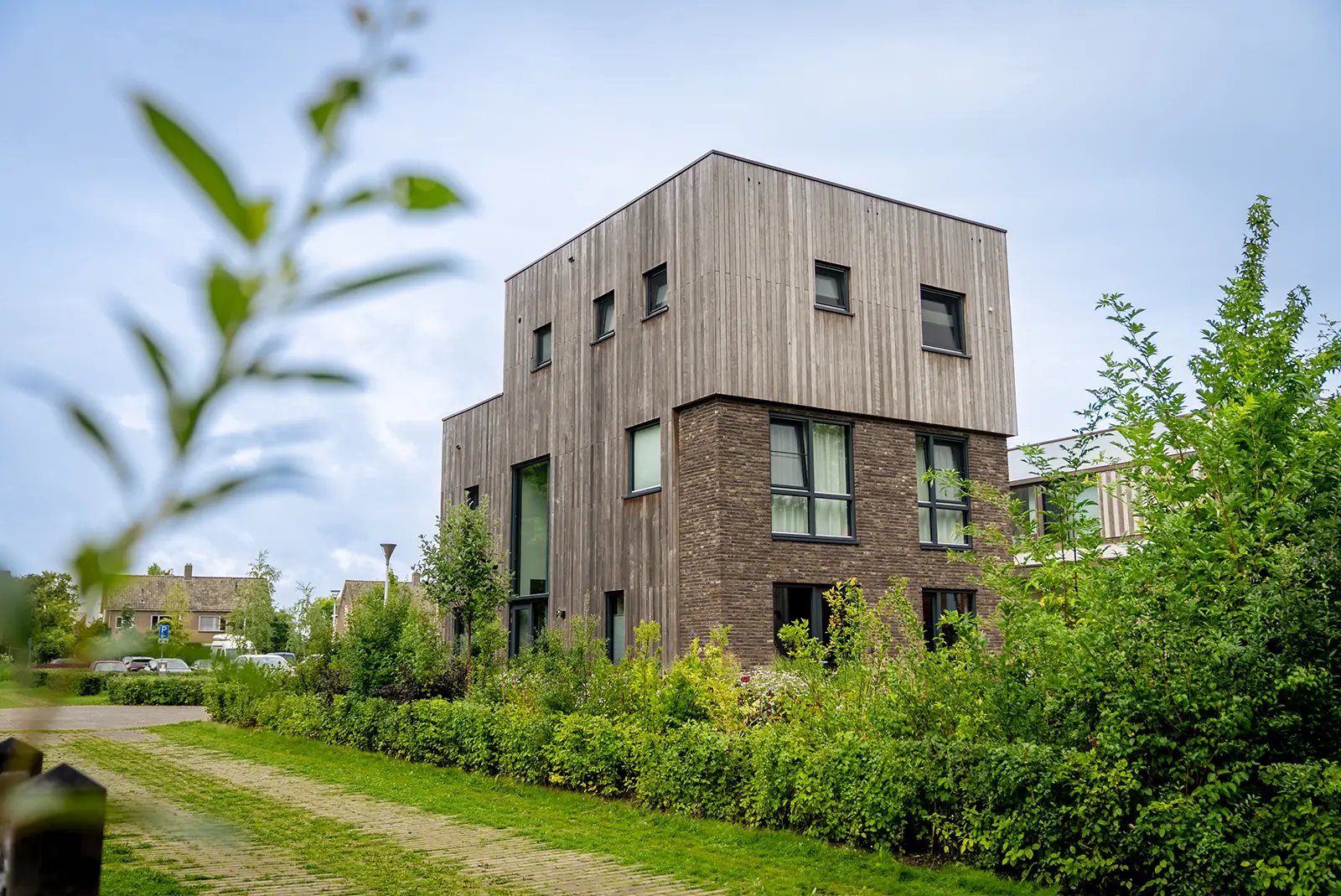 Zijaanzicht van een kubistische woning in Deventer met strakke lijnen, houten gevelbekleding en grote glaspartijen. Gebouwd door Mensink Bouwbedrijf.