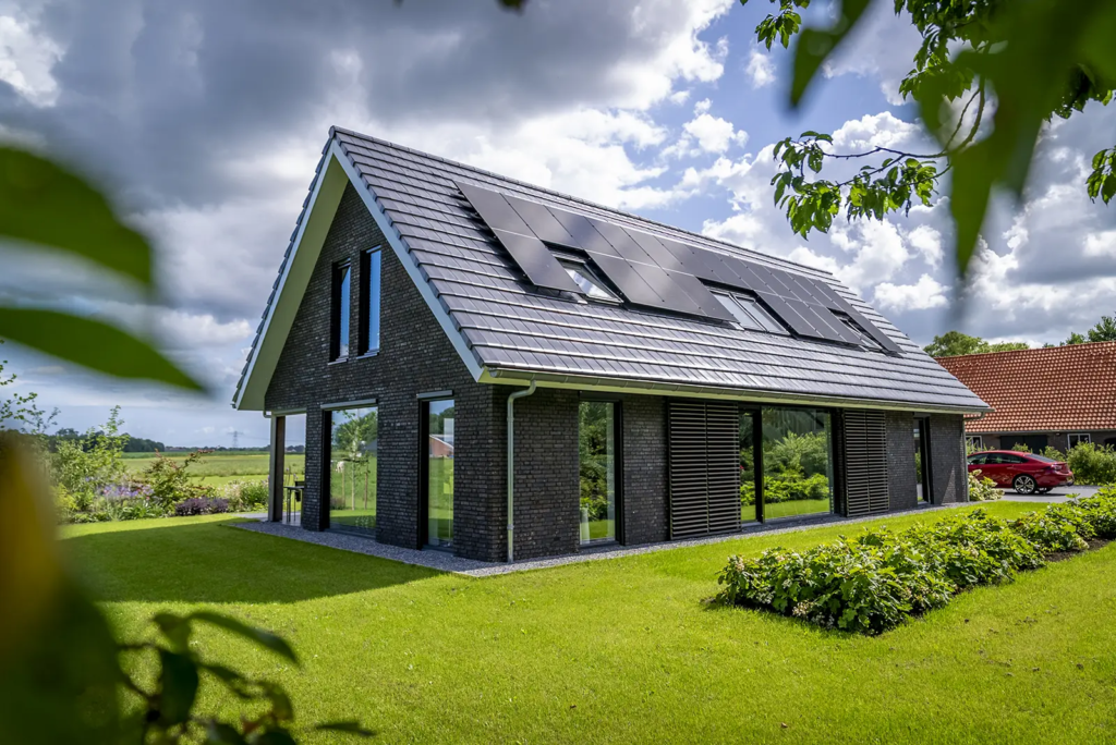 Zijaanzicht van woning met zonnepanelen en groene tuin, gerealiseerd door Mensink Bouwbedrijf in Olst.
