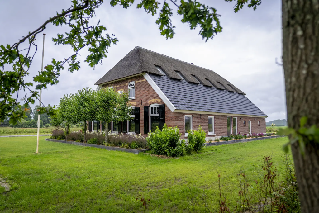 Vooraanzicht van karakteristieke woonboerderij met rieten wolfsdak in Okkenbroek.