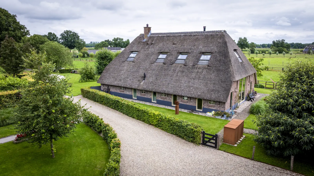 Zijaanzicht van traditionele woonboerderij met rieten dak in het buitengebied van Okkenbroek. Erfontwikkeling door Mensink.