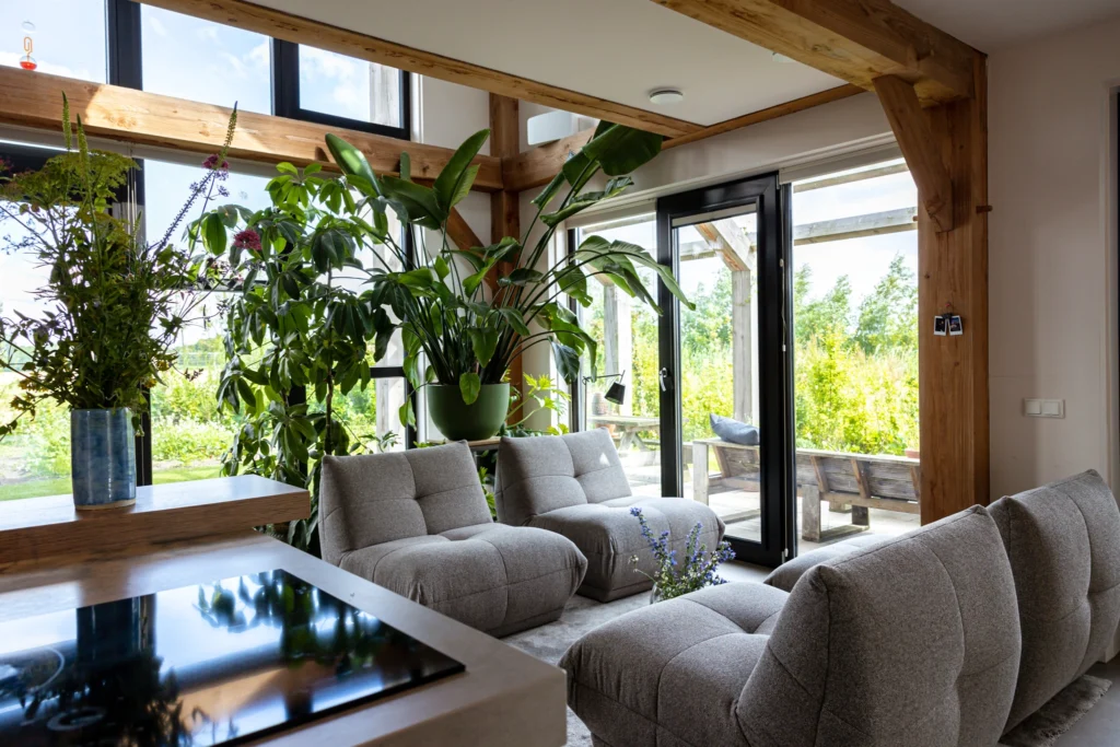 Zithoek met grote raampartijen en veel groen in de houten woning in Olst.